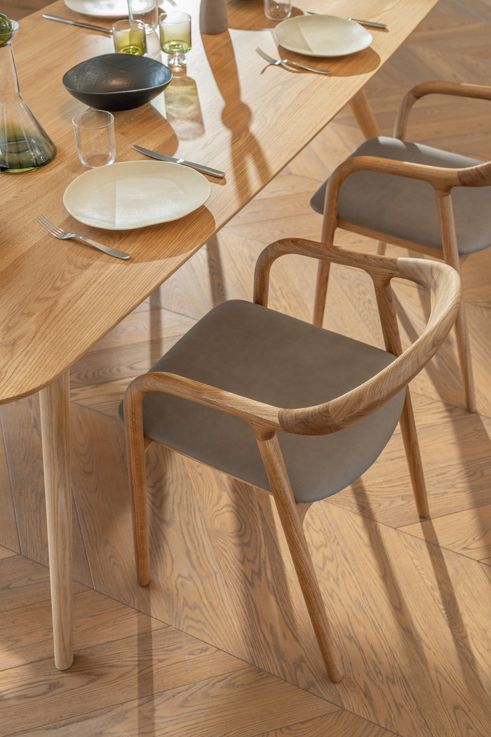 Sculptural armrests shaped in solid oak, walnut, or smoked ash.